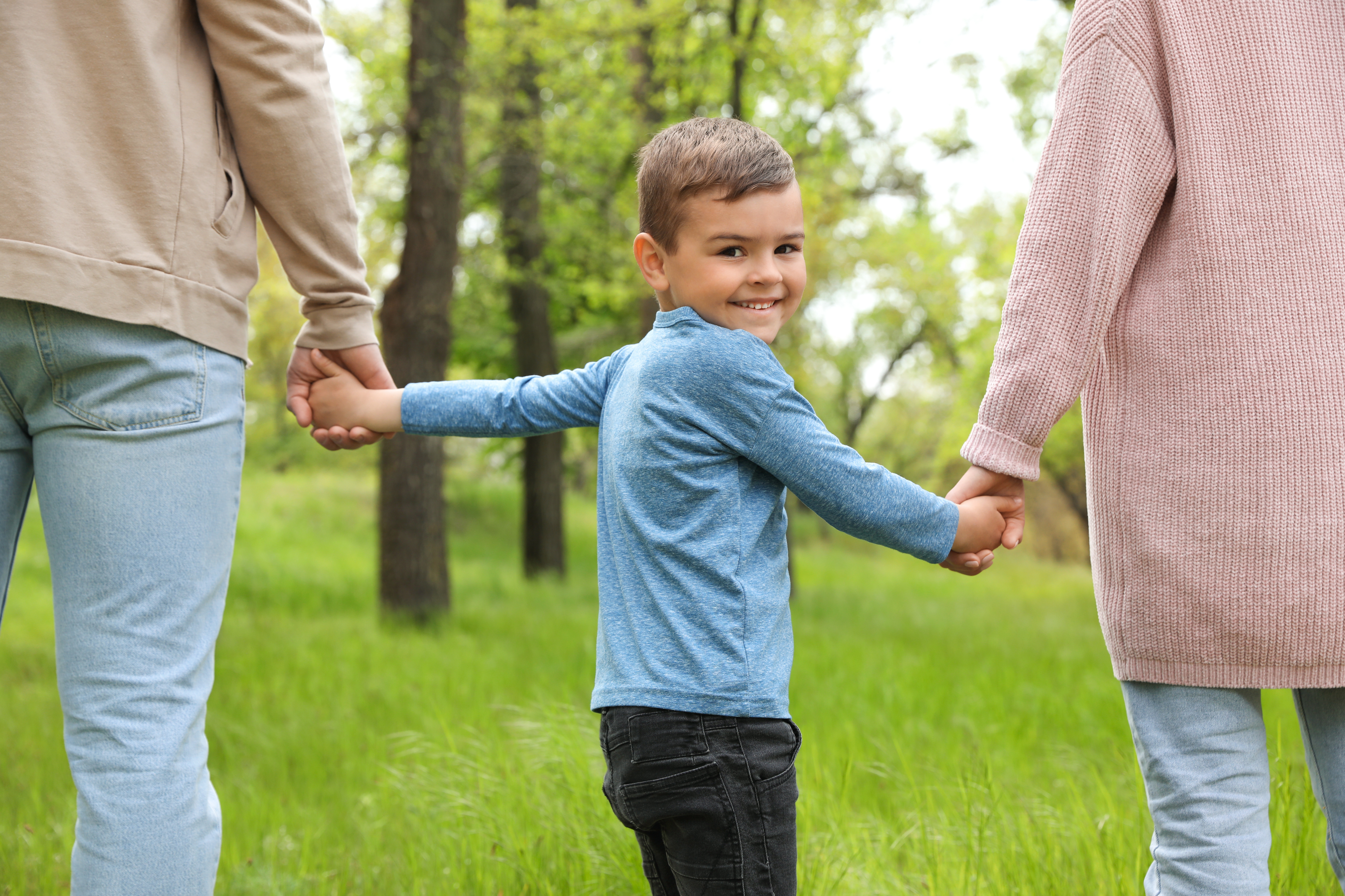Kid holding hands with parents
